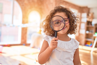 Child holding magnify glass - search for childcare
